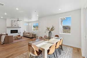 Dining room featuring light wood-type flooring, ceiling fan, a glass covered fireplace, and recessed lighting