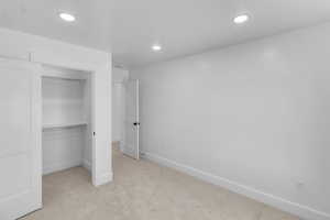 Bedroom 2 with light carpet, recessed lighting, and a spacious closet