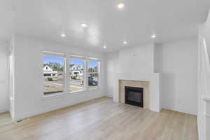 Living room with recessed lighting, a glass covered fireplace, and light wood-style flooring