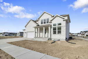View of front of home featuring stone siding, concrete driveway, covered porch, a residential view, and an attached garage