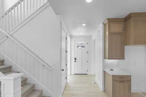 Entryway featuring light wood finished floors, stairway, and recessed lighting