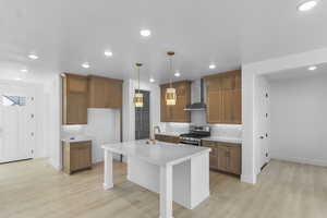 Kitchen with warm cabinetry, a kitchen breakfast bar, decorative light fixtures, recessed lighting, and stainless steel gas range
