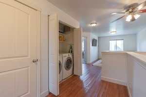 Laundry area featuring light wood-style flooring, a textured ceiling, ceiling fan, and washer and clothes dryer