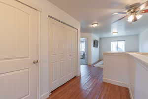 Hallway featuring dark wood-style floors, a textured ceiling, and an upstairs landing