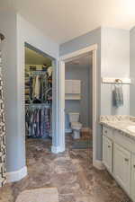Bathroom featuring a textured ceiling, vanity, and dark stone finish floors