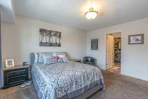 Bedroom with dark colored carpet, a spacious closet, and a textured ceiling