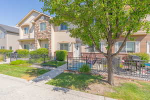 View of front of property featuring stone siding, a fenced front yard, and stucco siding