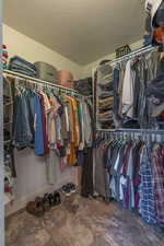 Walk in closet featuring dark stone finish floors