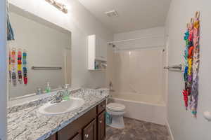 Bathroom with a textured ceiling, vanity, and bathtub / shower combination