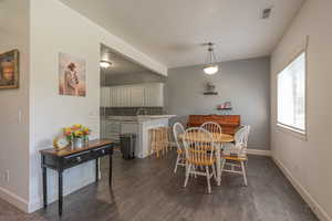 Dining room featuring dark wood-style flooring, a textured ceiling, and beamed ceiling