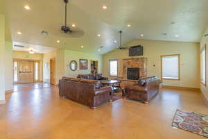 Living room featuring a textured ceiling, a stone fireplace, recessed lighting, and ceiling fan