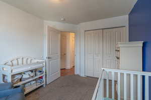 Carpeted bedroom featuring a textured ceiling and a closet