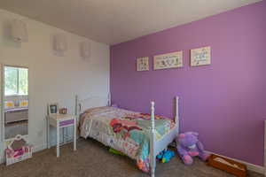Carpeted bedroom featuring a textured ceiling and baseboards