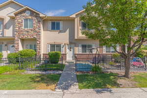 View of front of home with a fenced front yard, stucco siding, and stone siding