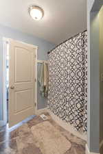 Bathroom featuring a textured ceiling and stone finish flooring