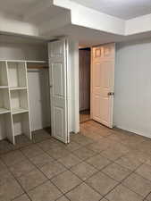 Unfurnished bedroom featuring light tile patterned floors, a textured ceiling, and a closet