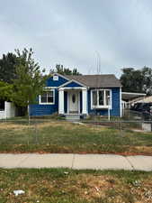 Bungalow with a fenced front yard, an attached carport, roof with shingles, and board and batten siding