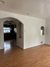 Spare room featuring arched walkways, a textured ceiling, and light wood-type flooring