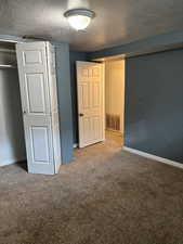 Unfurnished bedroom with a textured ceiling, carpet floors, and a closet