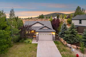 View of front facade with stone siding, a garage, driveway, and a front yard