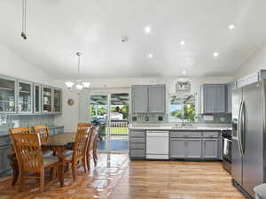 Kitchen featuring gray cabinets, backsplash, vaulted ceiling, stainless steel appliances, and recessed lighting