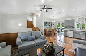 Living room with lofted ceiling, light tile patterned floors, a ceiling fan, stairs, and a chandelier