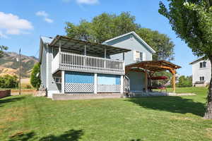 Rear view of property featuring a deck and a yard