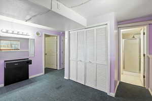 Unfurnished bedroom with dark carpet and a closet