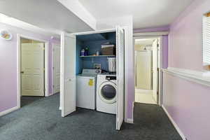 Washroom featuring dark colored carpet and washing machine and clothes dryer