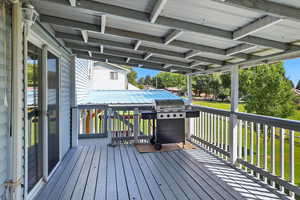 Wooden terrace featuring area for grilling and a lawn