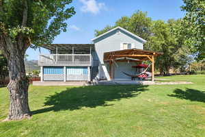 Rear view of house with a wooden deck and a yard