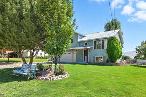 View of front facade with a front yard, a mountain view, an attached garage, a metal roof, and covered porch