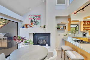 Dining space featuring rail lighting, a high ceiling, a glass covered fireplace, and light wood-style floors