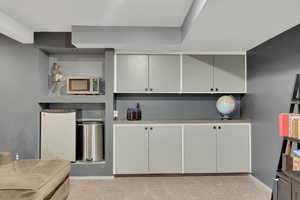 Theater room featuring light carpet, stainless steel microwave, white cabinetry, and freestanding refrigerator