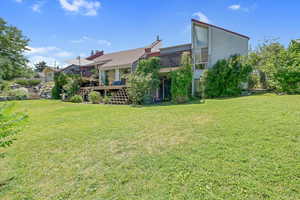 View of grassy yard featuring a wooden deck and stairs