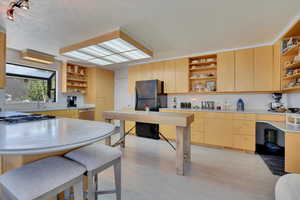 Kitchen with open shelves, light countertops, freestanding refrigerator, and light brown cabinetry