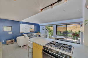 Kitchen featuring stainless steel gas range oven, light countertops, track lighting, light wood-style floors, and open floor plan