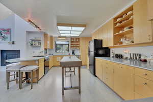 Kitchen featuring open shelves,Birdseye Maple Cabinets, a breakfast bar area, gas range, and track lighting