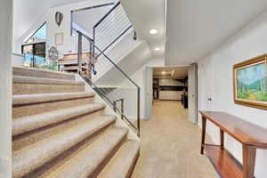 Stairs with carpet floors and recessed lighting
