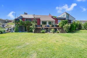 Back of house featuring stairs, a deck, a chimney, and a yard