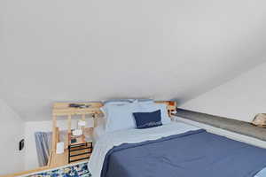 Bedroom with vaulted ceiling and a textured ceiling