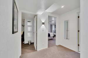 Hall featuring carpet flooring and a textured wall