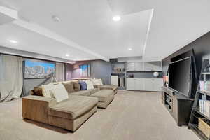 Living area featuring light colored carpet, recessed lighting, and bar