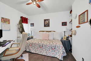 Carpeted bedroom with a ceiling fan and a desk