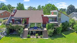 Rear view of house with stairs, a yard, a wooden deck, and roof with shingles
