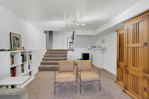 Living area with carpet, stairway, and a textured ceiling