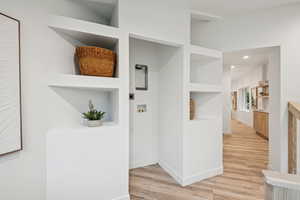 Hall featuring built in features, light wood-type flooring, and recessed lighting