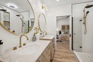 Ensuite bathroom with walk in shower, light wood-type flooring, two vanities, and recessed lighting