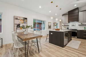Kitchen featuring pendant lighting, recessed lighting, a kitchen island with sink, appliances with stainless steel finishes, and light wood-style flooring