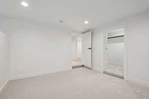 Unfurnished bedroom with light carpet, recessed lighting, and a walk in closet